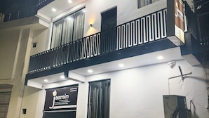 A two-story building with a sign for 'Jasmin Luxury Stay' and multiple potted plants in front. - Jasmin A Luxury Stay (Agra)
