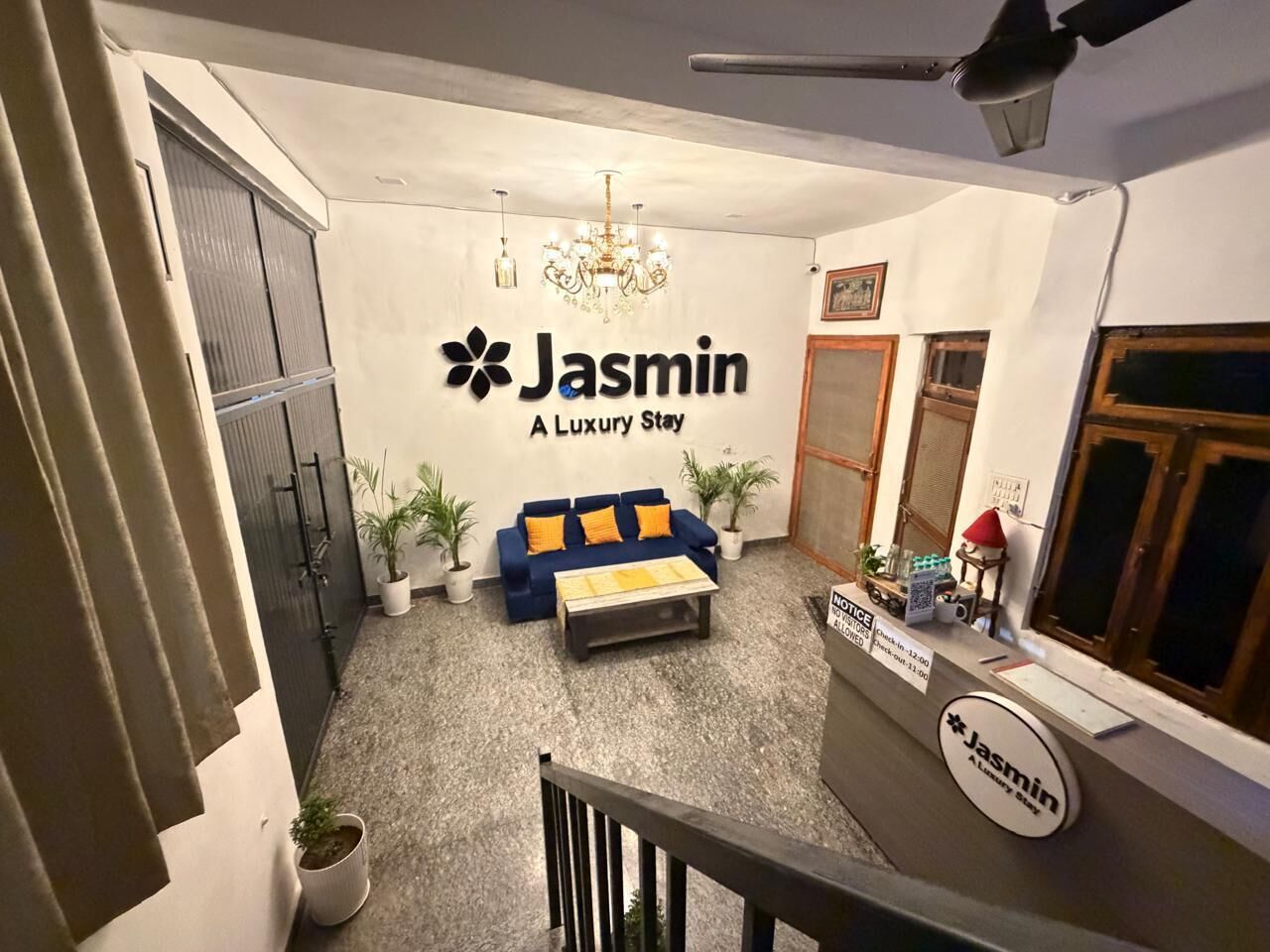 Un interno moderno con un divano blu, un lampadario e un cartello con la scritta 'Jasmin A Luxury Stay'.