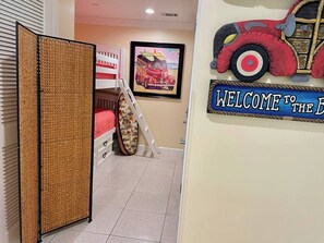 Una habitación con literas, un cuadro con un coche antiguo y un letrero de bienvenida.