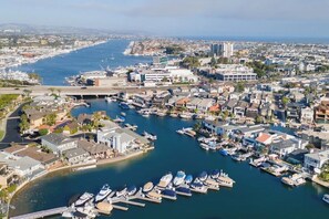 Uma marina com barcos atracados, rodeada por edifícios residenciais e uma ponte ligando à terra firme.