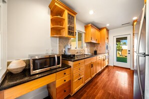 A kitchen with wooden cabinets, a microwave, a sink, and a refrigerator. - Mins To Beach W/Jacuzzi, Large Yard,Parking & AC! (Oceanside)