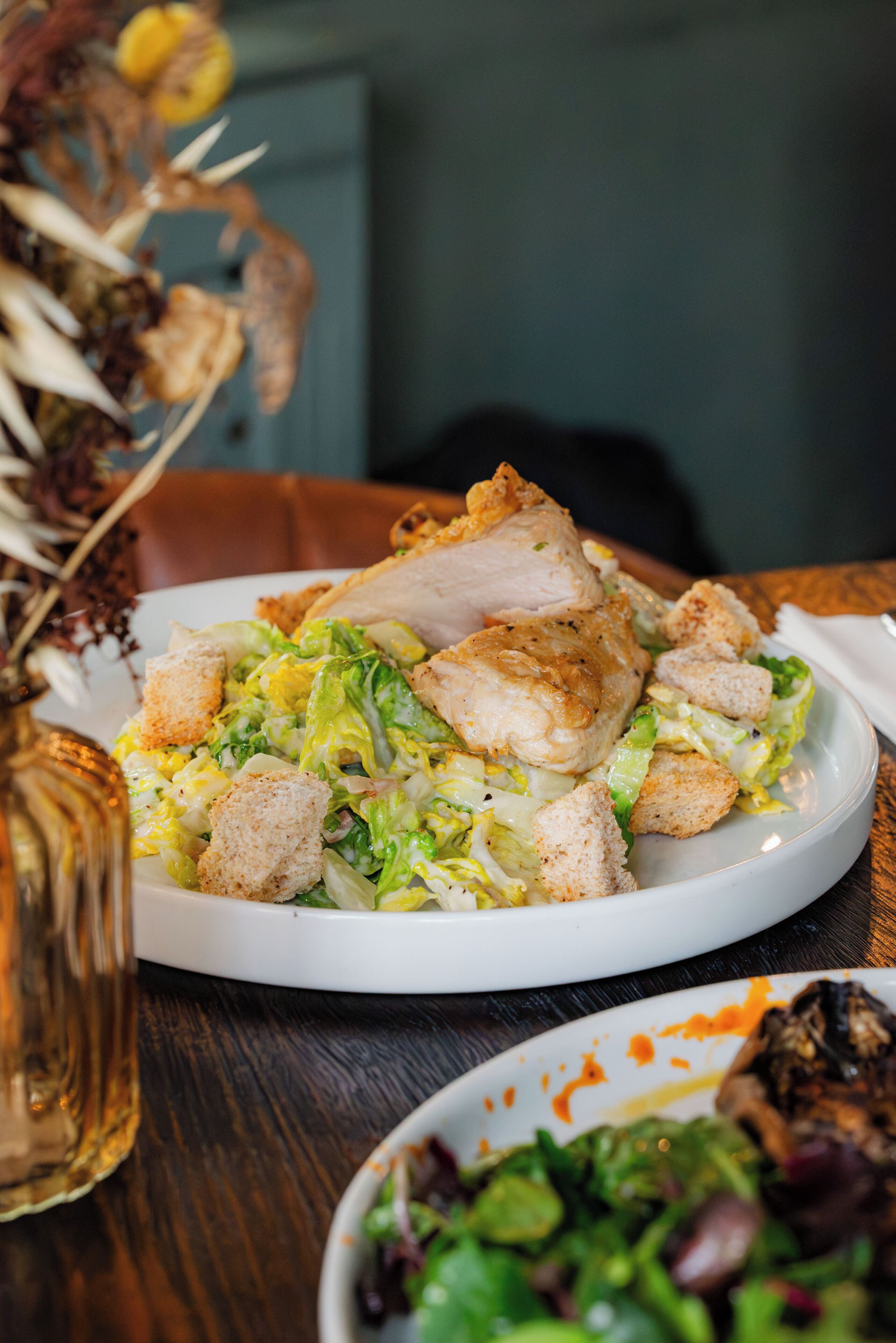 Een bord eten met croutons en een stukje kip op een wit bord.