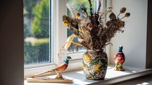 A window sill with a decorative vase, a bird figurine, and a colorful bottle. - The Huntsman (Strumpshaw)