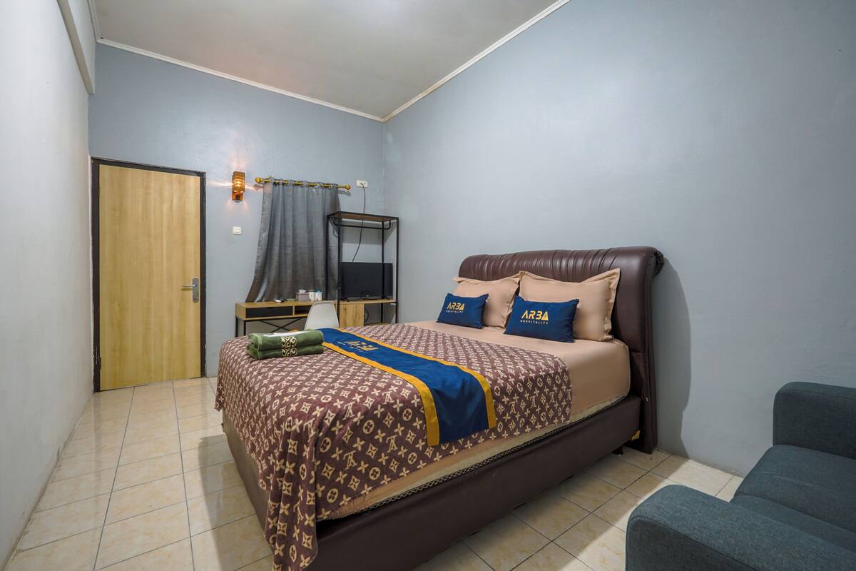 A bedroom with a bed, a desk, a chair, and a wardrobe.