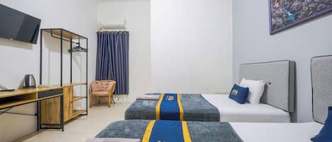 A hotel room with two beds, a desk, a chair, a TV, and a painting on the wall.