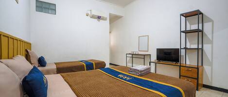 A hotel room with two beds, a TV, a small table, and a shelf.