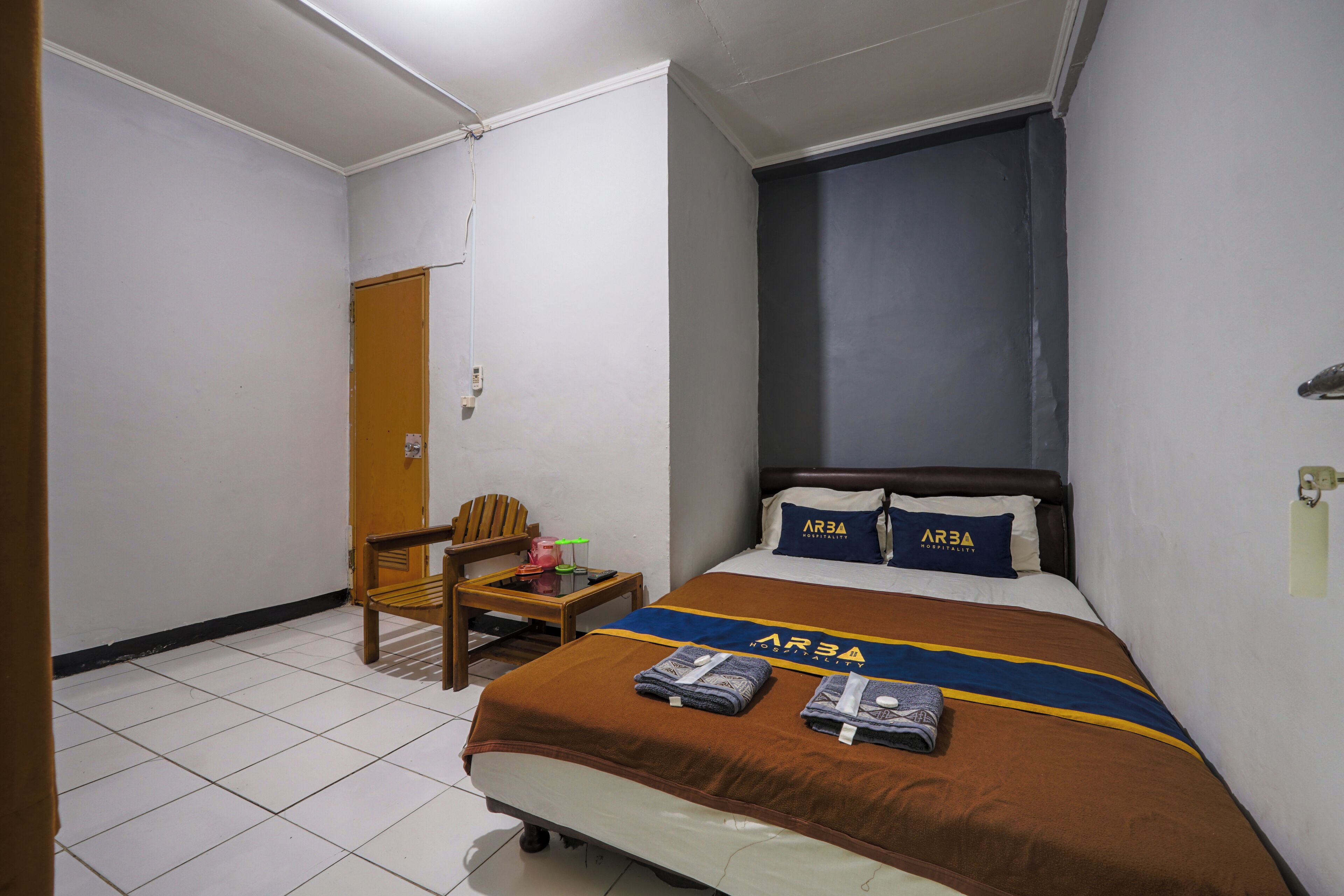 Une chambre d’hôtel avec un lit, une chaise, une petite table et une fenêtre.