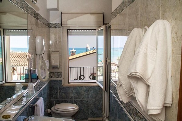 A bathroom with a view of the sea, a toilet, a sink with a soap dispenser, and a towel rack. - hotel Cristall (San Benedetto del Tronto)