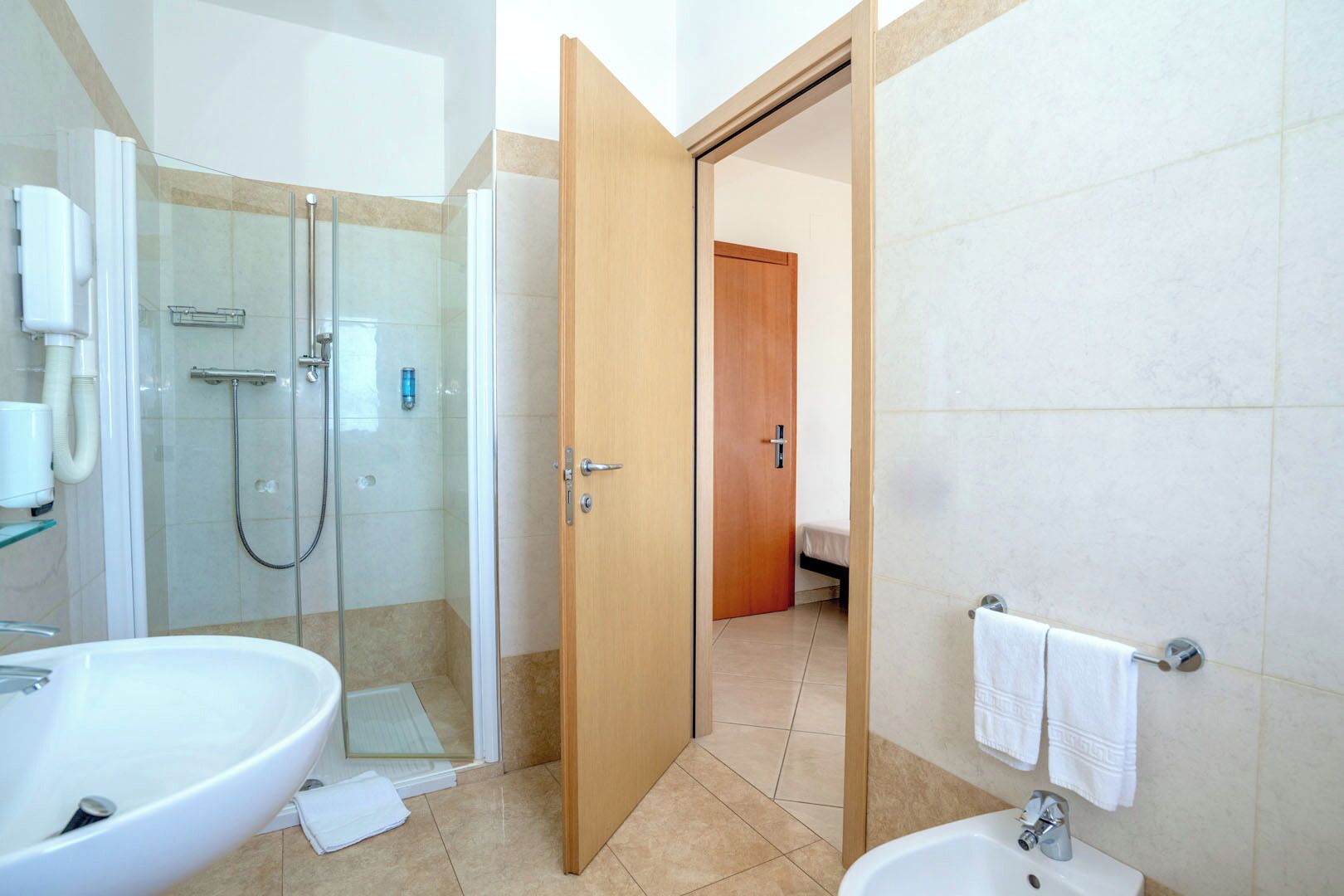 A modern bathroom with a glass-enclosed shower, a large bathtub, and a separate sink area.