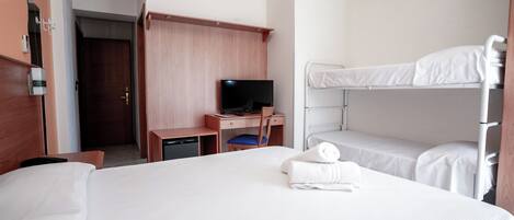 A hotel room with a bed, a desk with a television, a bunk bed, and a wardrobe.