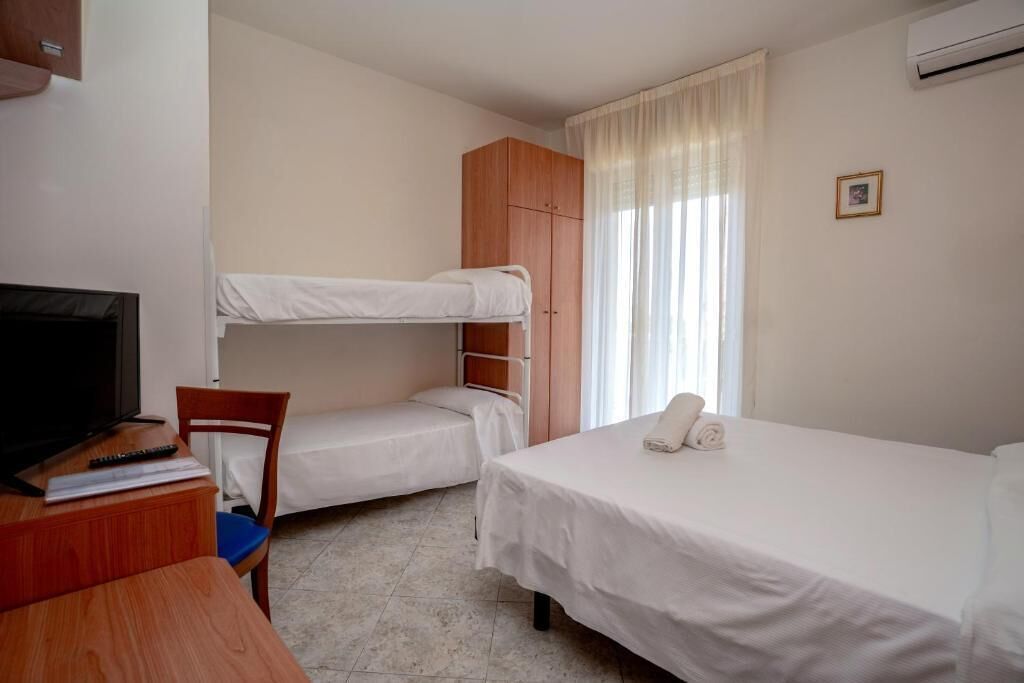 Quarto com beliches, escrivaninha com televisão e uma cadeira.