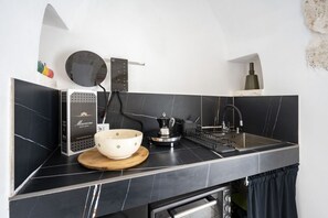 A modern kitchen with a black countertop, a coffee maker, a kettle, and a sink. - GuestHost - Trullo Angelica (Martina Franca)