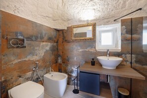 Ein Badezimmer mit Toilette, Bidet, Waschbecken, Spiegel und Handtuchhalter.