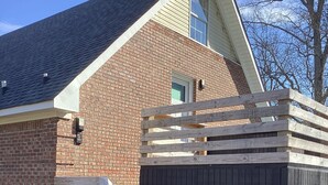 A brick house with a wooden deck and a black fence.