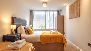 Un dormitorio con cama, mesitas de noche, una ventana y una obra de arte colgada en la pared.