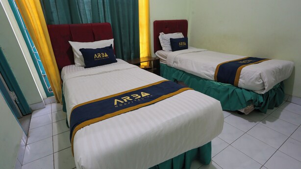 Two single beds with matching headboards and footboards, each with a pillow and a bedspread featuring a logo.