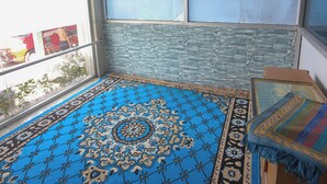 A room with a patterned blue carpet, a glass door, and a view of the outside.
