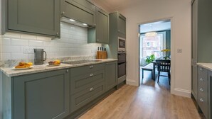 Eine Küche mit grauen Schränken, einer weißen Fliesenrückwand und Holzboden.