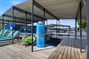 A covered outdoor area with a wooden deck, a pool, and a boat dock. - Lakeside Serenity Dock Days & Firepit Nights (Gravois Mills)