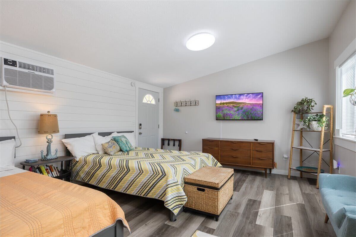 A bedroom with a bed, bedside table, lamp, dresser, and a painting on the wall.