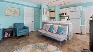 A compact living space with a kitchenette, a sofa, a small armchair, and a wooden ceiling fan. - Lakeside Serenity Dock Days & Firepit Nights (Gravois Mills)