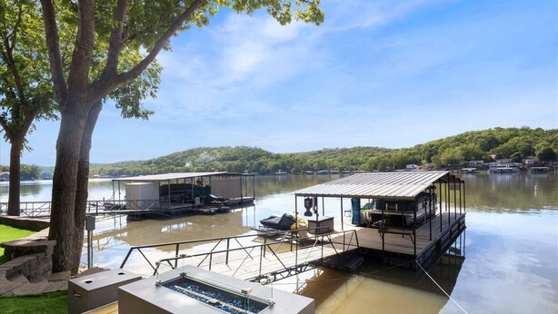A lakeside deck with a grill, a covered seating area, and a dock extending into the water. - Lakeside Serenity Dock Days & Firepit Nights (Gravois Mills)