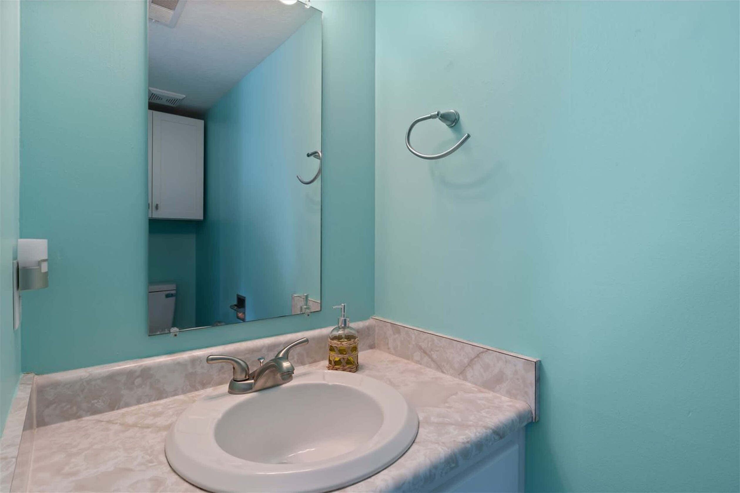 Une salle de bain avec un lavabo blanc, un miroir et un porte-serviettes fixé au mur.