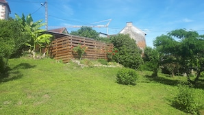 Un cadre rural avec une structure en bois, un bâtiment en pierre et une végétation luxuriante.