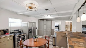 Una cocina moderna con una isla central, electrodomésticos de acero inoxidable y un comedor con una mesa redonda y sillas.
