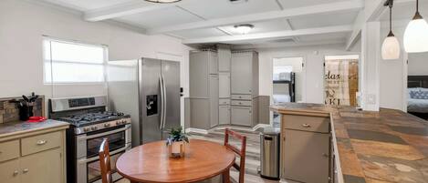A modern kitchen with a central island, stainless steel appliances, and a dining area with a round table and chairs.
