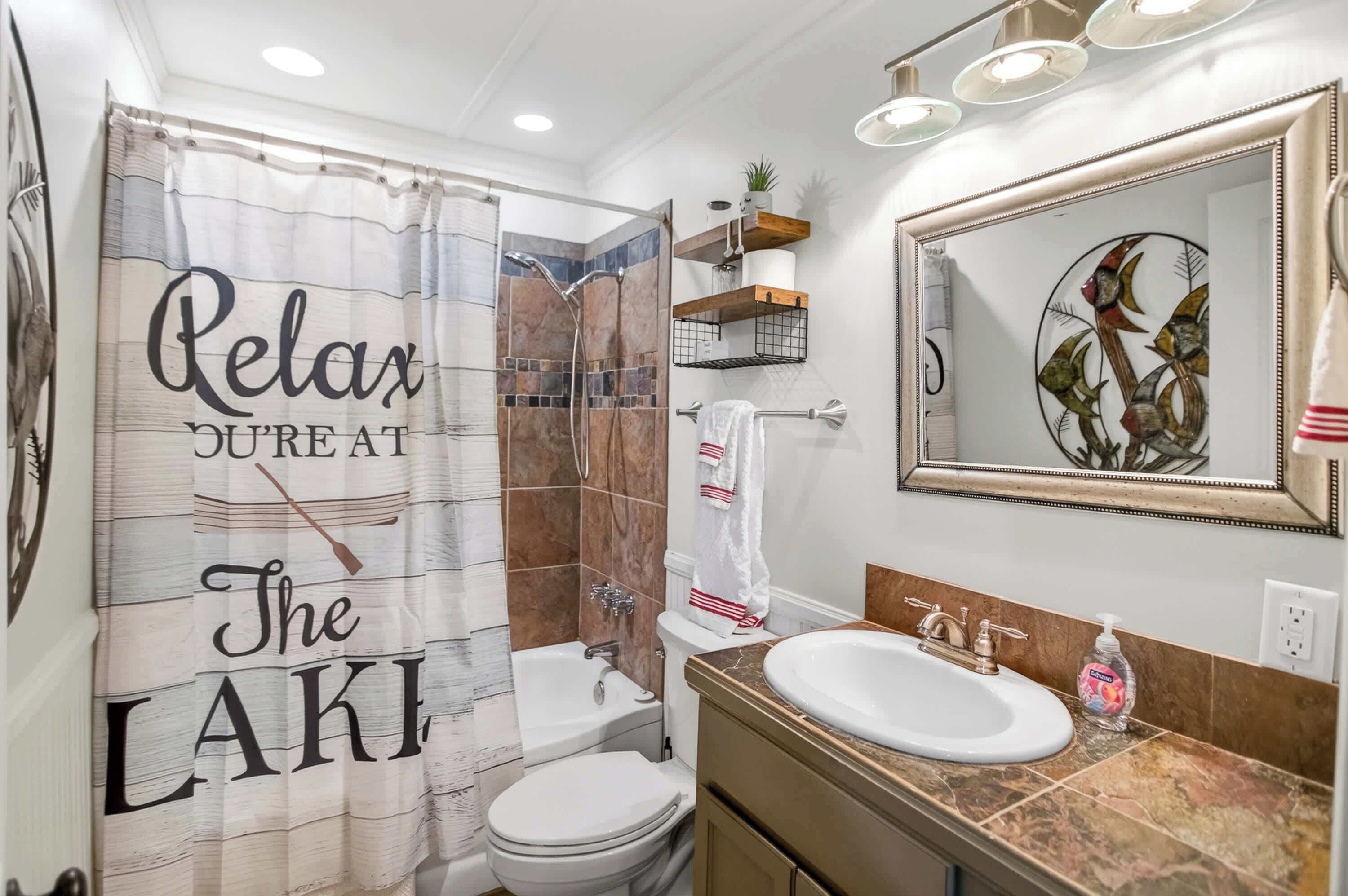A bathroom with a shower curtain, a toilet, a sink, and a mirror.