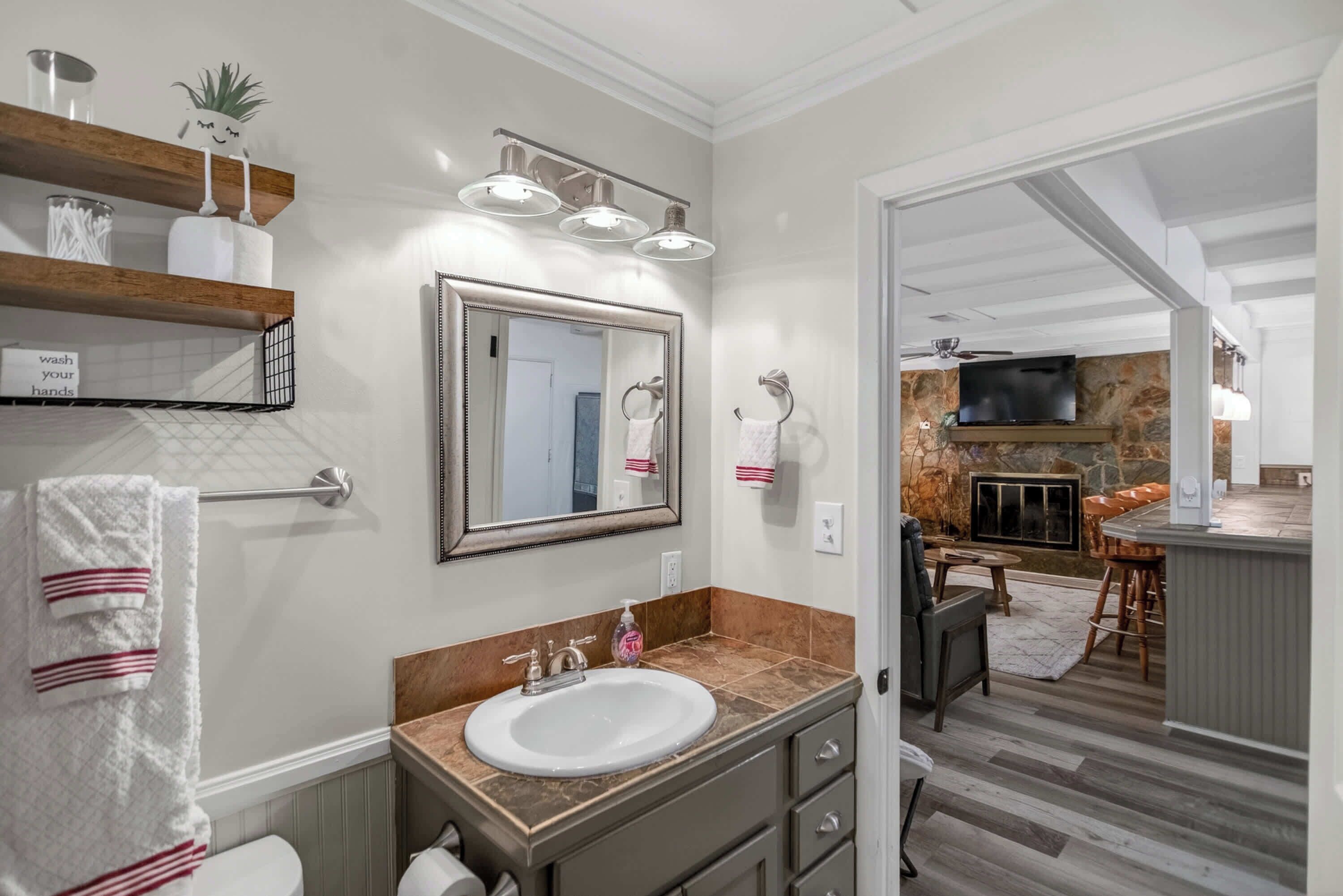 A bathroom with a sink, mirror, towel rack, and a shelf with toiletries.