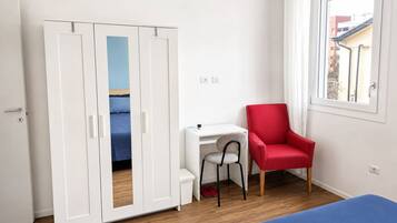 Una habitación con cama, escritorio, silla roja y armario.