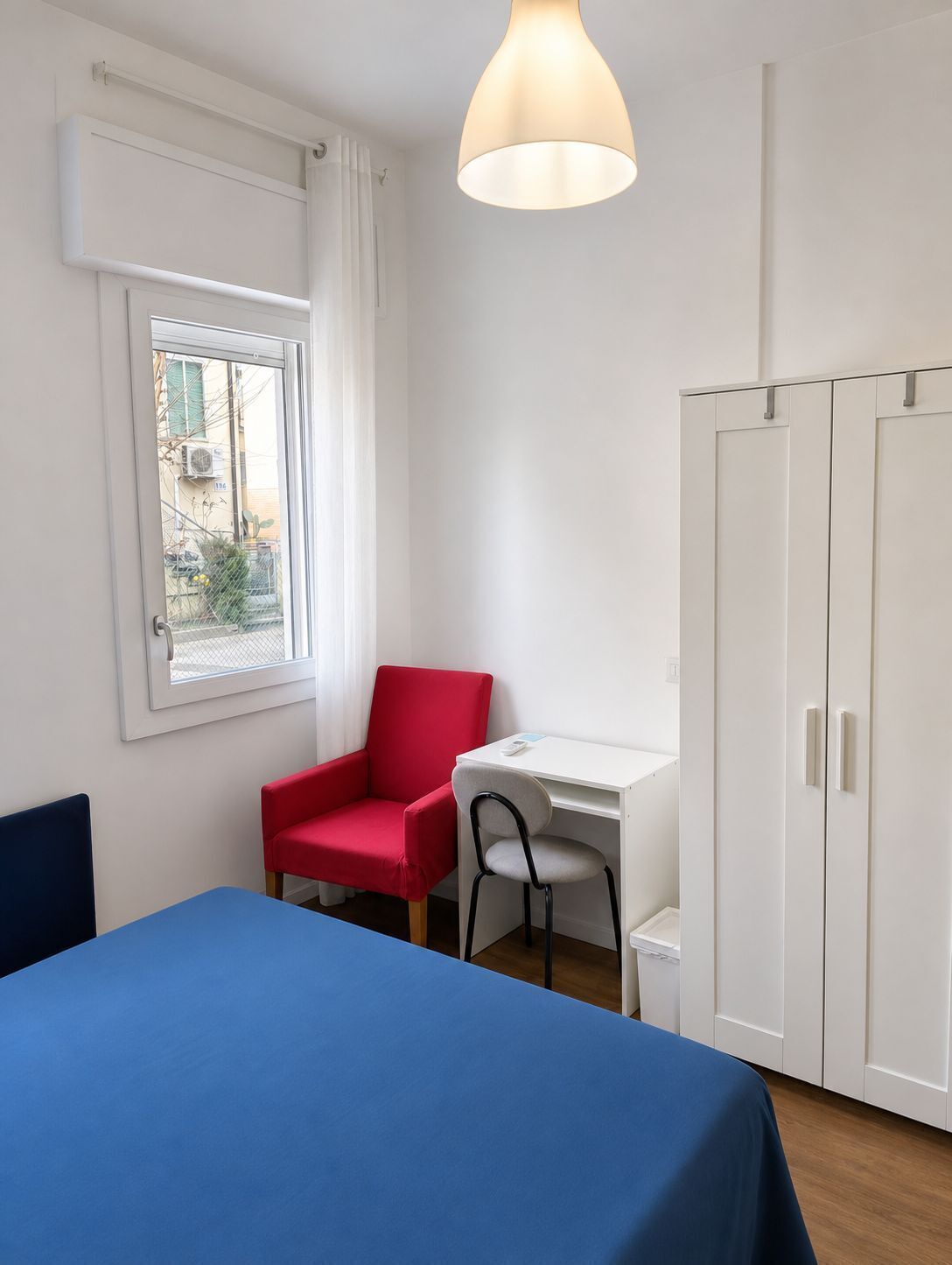 A room with a bed, a desk, a chair, and a wardrobe.