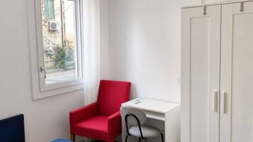 A room with a bed, a desk, a chair, and a wardrobe.