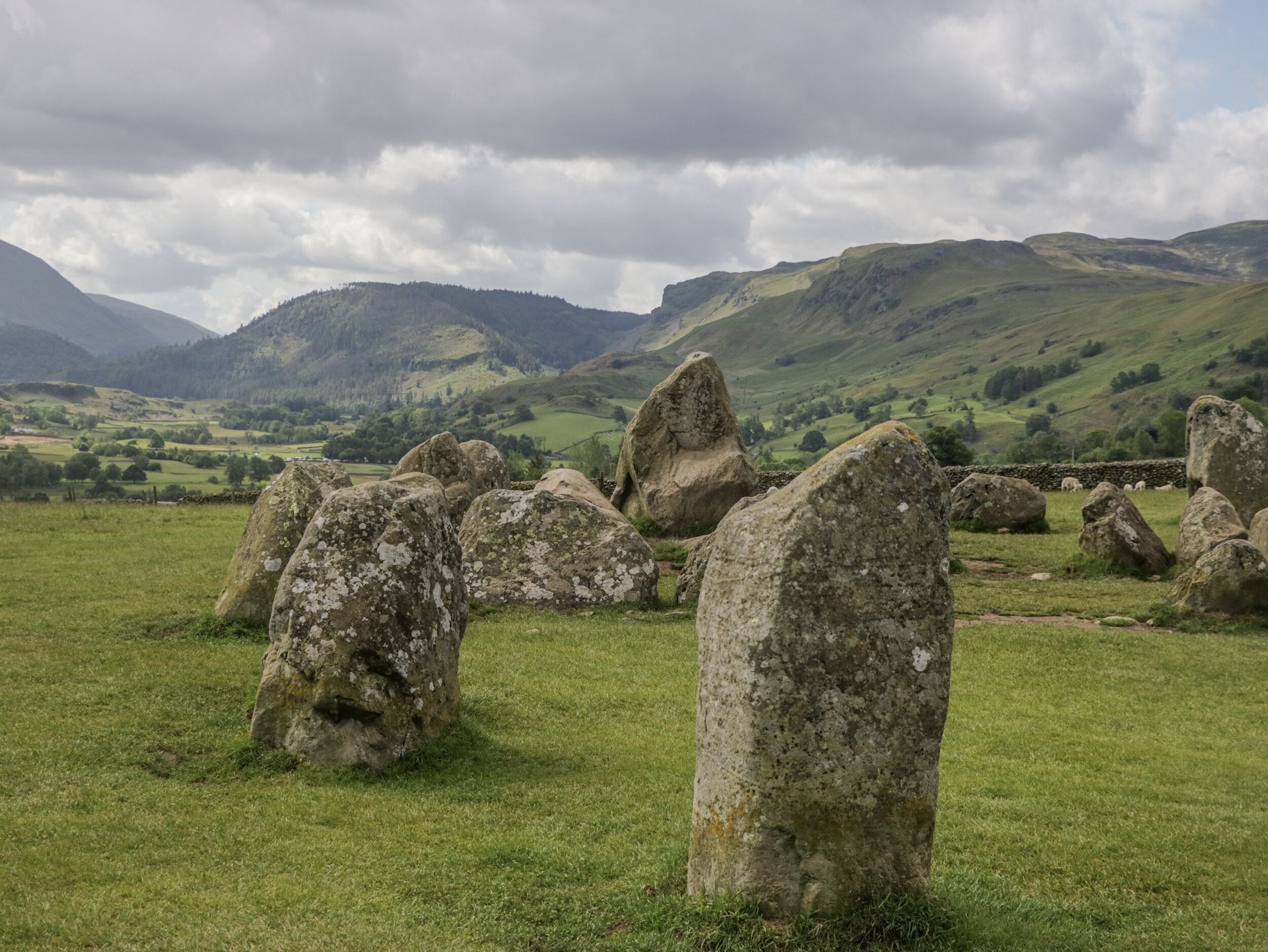 A stone circle in a grassy field with rolling hills in the background.