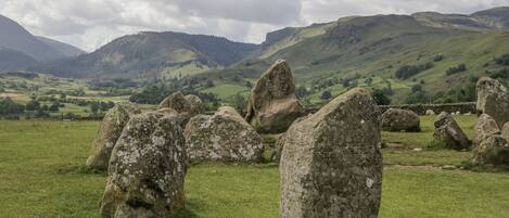 A stone circle in a grassy field with rolling hills in the background.