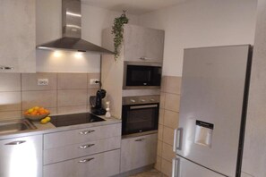 A modern kitchen with a stainless steel range hood, a built-in microwave, an oven, and a refrigerator.