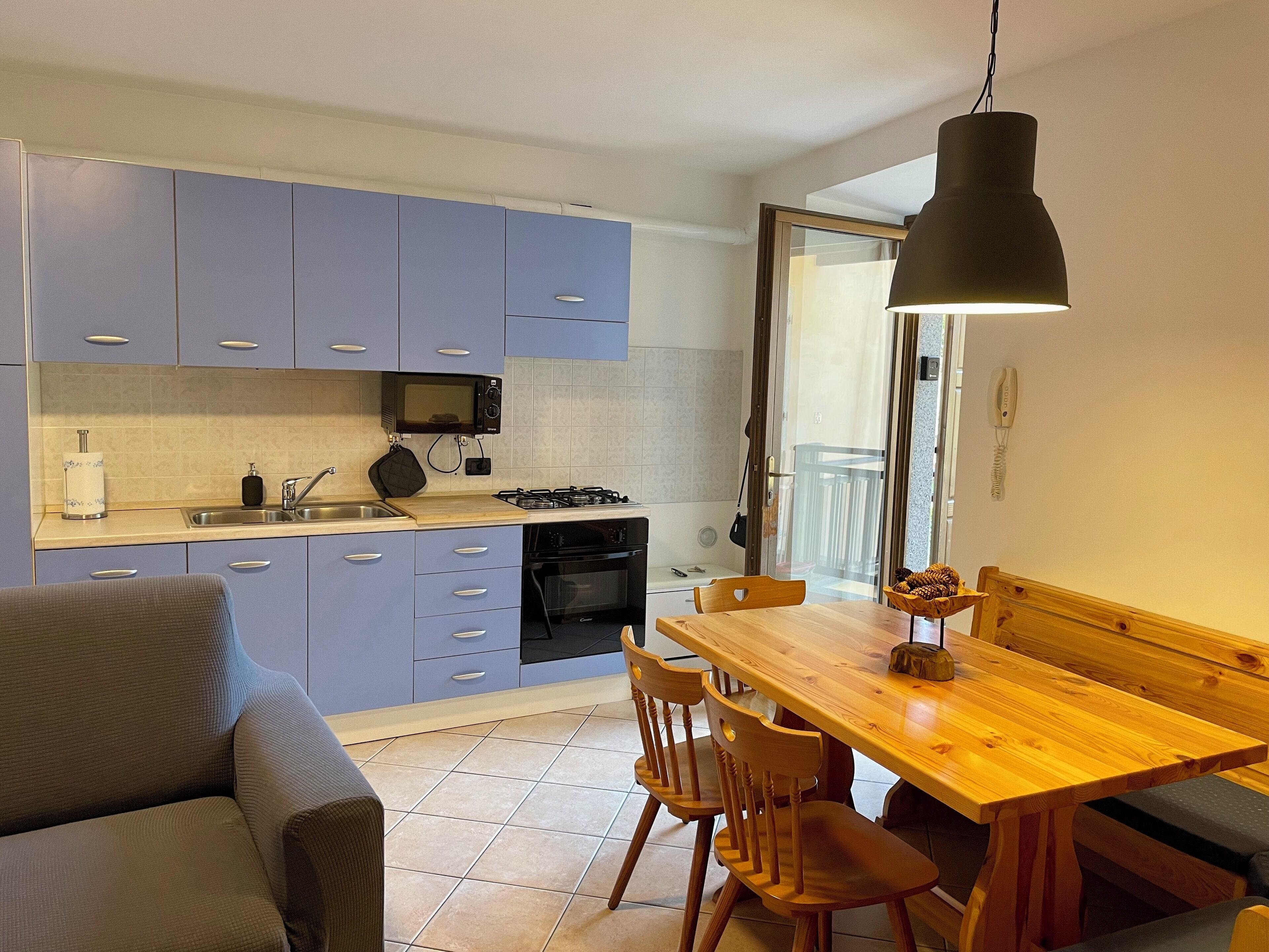 Una cucina funzionale con mobili blu, un tavolo da pranzo in legno e un divano.