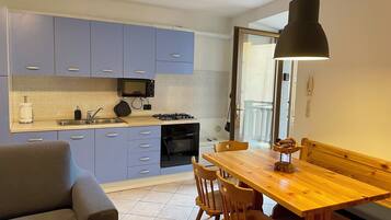 Una cucina funzionale con mobili blu, un tavolo da pranzo in legno e un divano.