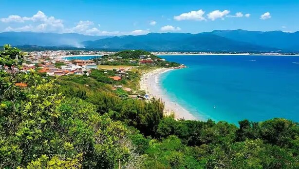 Una località costiera con una spiaggia, circondata dalle montagne.
