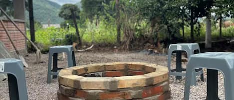 A circular fire pit surrounded by gravel, with grey plastic stools arranged around it.