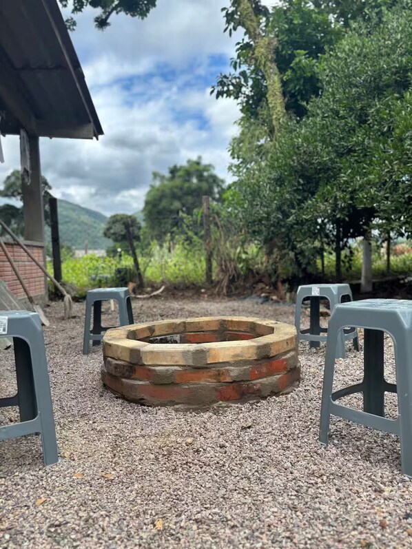 A circular fire pit surrounded by gravel, with grey plastic stools arranged around it.