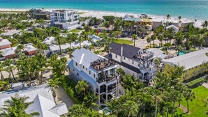 A coastal resort with multiple buildings, a beach, and palm trees.