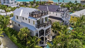 A multi-story house with a large balcony, a swimming pool, and a view of the ocean.