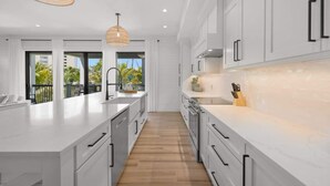 A modern kitchen with white cabinetry, a large island, and a view of the outdoors.