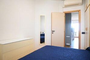 Ein Schlafzimmer mit Bett, Schminktisch, Spiegel und einer Tür zum Badezimmer.