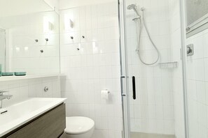 Un bagno moderno con doccia vetrata, lavandino bianco e water.