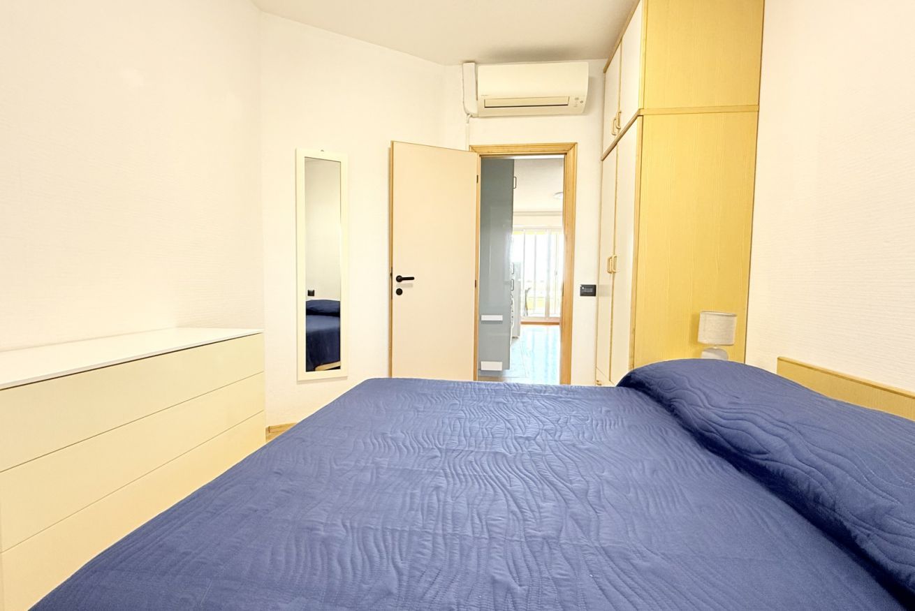 Un dormitorio con cama, puerta, espejo y aire acondicionado de pared.