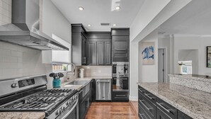 A modern kitchen with dark cabinetry, stainless steel appliances, and a granite countertop. - The Blue Heaven/ Poolside Retreat Near Brickell / Sleeps 13 (Miami)
